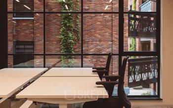 Kantoorpand aan de Karl Weisbardstraat 181-201 in Rotterdam Centrum met grote ramen die uitzicht bieden op een bakstenen gebouw. Ruime werkplekken en moderne kantoormeubels maken het ideaal om kantoorruimte te huren.