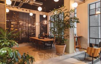 Stijlvolle vergaderruimte in kantoorpand Karl Weisbardstraat 181 - 201, Rotterdam Centrum met lange houten tafel, moderne verlichting en grote planten. Ideaal voor kantoorruimte huren met een uitnodigende sfeer.