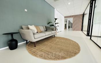 Een moderne entree van een kantoorpand op Kruisplein 480, Rotterdam Centrum, met een stijlvolle zitbank en ronde vloerkleed. Ideaal voor wie kantoorruimte wil huren in een aantrekkelijke omgeving.