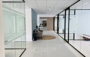 Kantoorruimte huren aan Kruisplein 480, Rotterdam Centrum, met glazen wanden en moderne afwerking. Gezellige zithoek zichtbaar, ideaal voor informeel overleg.