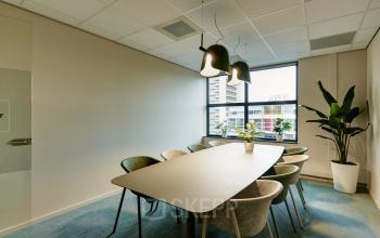 Moderne vergaderruimte in een kantoorpand op Weena 335, Rotterdam Centrum, met grote tafel, comfortabele stoelen en veel natuurlijke lichtinval. Geschikt voor bedrijfsmatig gebruik en te huur als kantoorruimte.