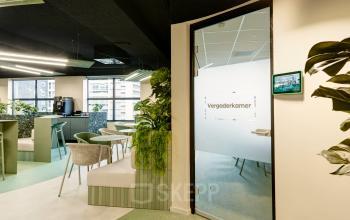 Binnenkijken in het kantoorpand op Weena 335, Rotterdam Centrum: moderne gemeubileerde vergaderruimte met groene accenten en veel lichtinval. Ideaal voor kantoorruimte huren.