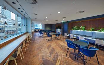 Moderne kantoorlounge met houten vloer, comfortabele stoelen en planten in kantoorpand aan Blaak 555, Rotterdam Centrum.