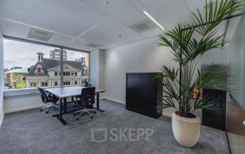 Kantoorruimte huren op Blaak 555, Rotterdam Centrum, met grote ramen, twee bureaus en kasten, voorzien van natuurlijke lichtinval en uitzicht op historische gebouwen.