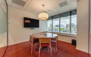 Vergaderruimte in Blaak 555, Rotterdam Centrum, ingericht met ronde tafel en stoelen, voorzien van moderne apparatuur en uitzicht op de stad. Ideale locatie voor kantoorruimte huren.