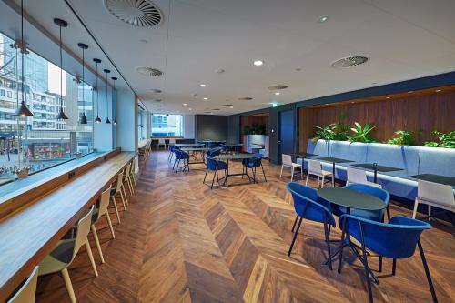 Moderne kantoorlounge met houten vloer, comfortabele stoelen en planten in kantoorpand aan Blaak 555, Rotterdam Centrum.
