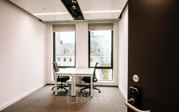 Kantoorruimte te huur op Coolsingel 65 in Rotterdam Centrum, met een modern bureau en twee stoelen, uitzicht op de stad door grote ramen.