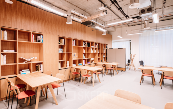 Lichte kantoorruimte in kantoorpand, Hoogstraat 185, Rotterdam Centrum, met houten tafels en stoelen, omringd door open boekenplanken. Ideaal voor wie kantoorruimte wil huren met een moderne uitstraling.