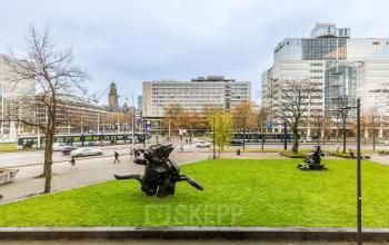 Uitzicht op het kantoorpand aan Weena 87 in Rotterdam Centrum, met opvallende sculpturen en voorbijgangers op de achtergrond. Ideale locatie om kantoorruimte te huren in een dynamisch stadsdeel.