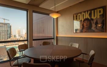 Vergaderruimte in een kantoorpand op Coolsingel 139, Rotterdam Centrum met ronde tafel, stoelen en uitzicht op de stad. Ideaal voor kantoorruimte huren met een inspirerende setting.