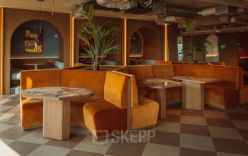 Moderne kantoorruimte huren in Rotterdam Centrum aan Coolsingel 139 met stijlvolle, gemeubileerde zitbanken en tafels in een warme sfeer.
