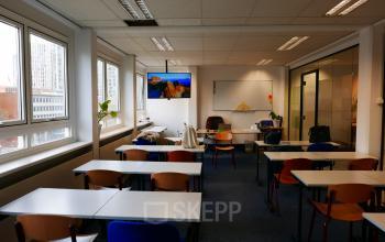 Ruimte in een kantoorpand aan Wijnhaven 76, Rotterdam Centrum met tafels, stoelen en enkele groene planten. Grote ramen bieden veel natuurlijk licht. Ideaal voor kantoorruimte huren.