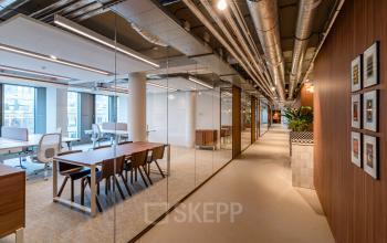 Moderne kantoorruimte in kantoorpand Stadhuisplein 9-23, Rotterdam Centrum met strak interieur en houten accenten voor huur, voorzien van glazen wanden en attente verlichting.