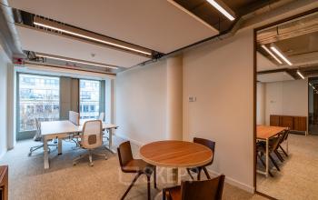 Kantoorruimte huren op Stadhuisplein 9-23 in Rotterdam Centrum met strakke inrichting, moderne houten tafels en stoelen. Grote ramen zorgen voor veel lichtinval. Ideaal voor een flexibele werkruimte.