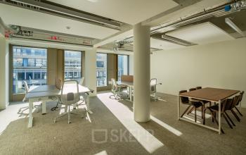 Ruime kantoorruimte met grote ramen op Stadhuisplein 9-23 in Rotterdam Centrum, voorzien van bureaus en stoelen, ideaal voor zakelijke activiteiten en kantoorruimte huren.