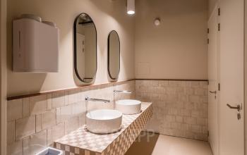 Moderne badkamer in kantoorpand Stadhuisplein 9-23, Rotterdam Centrum, met twee wastafels en spiegels. Beschikbaar voor kantoorruimte huren.