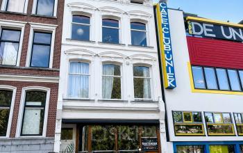 Gevel van een kantoorpand aan de Mauritsweg 33 A01 in Rotterdam Centrum, met klassieke architectuur naast moderne kleurrijke gebouwen. Ideaal voor wie kantoorruimte wil huren op een levendige locatie.