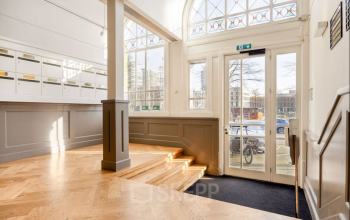 Ingang van het kantoorpand op Veerhaven 7, Rotterdam Centrum met hoge ramen die veel licht binnenlaten en houten vloer.