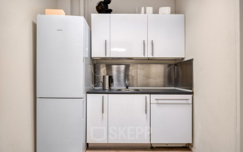 Compacte kitchenette in kantoorpand op Veerhaven 7, Rotterdam Centrum. Ideaal voor kleine pauzes tijdens het werk. Voorzien van koelkast en aanrechtblad. Geschikt bij kantoorruimte huren.