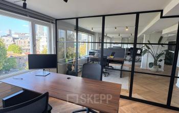Stijlvolle kantoorruimte met houten vloer in Rotterdam Centrum, op Westplein 12, met moderne bureaus en stoelen en uitzicht op de stad. Perfect om te huren als kantoorpand.