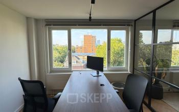 Moderne kantoorruimte met een groot bureau, twee comfortabele stoelen en een breed raam met uitzicht op de stad in het kantoorpand op Westplein 12, Rotterdam Centrum.