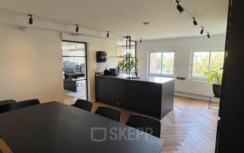 Moderne kantoorruimte op Westplein 12 in Rotterdam Centrum met ruime werktafels en zwart meubilair, omringd door grote ramen.