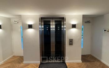 Entree van een kantoorpand met een lift aan Westplein 12, Rotterdam Centrum. De strakke houten vloer geeft een moderne uitstraling voor huur van kantoorruimte.