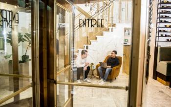 Zakelijke bespreking in een stijlvolle lounge van een kantoorpand op Coolsingel 104, Rotterdam Centrum, met twee mannen die overleggen.