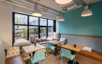 Gezellige gemeubileerde kantoorruimte huren op Westblaak 180, Rotterdam Centrum, met zithoek, tafels en stoelen bij grote ramen.