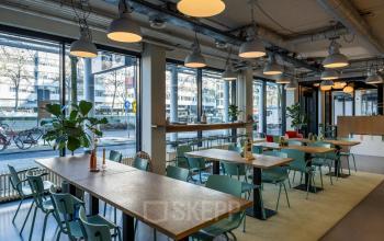 Kantoorruimte in Rotterdam Centrum aan Westblaak 180 met moderne inrichting en grote ramen. Ideaal om te huren als werkruimte, voorzien van tafels en stoelen onder sfeerverlichting.