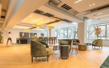 Kantoorruimte huren in kantoorpand op Beursplein 37, Rotterdam Centrum met moderne inrichting, zitplaatsen en verlichtingsinstallaties; twee personen in gesprek en een persoon bij de balie.