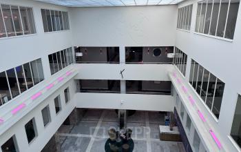 Kantoorruimte huren op Beursplein 37 in Rotterdam Centrum, smaakvol ingerichte kantoorpand met hoog plafond en veel natuurlijk licht. Ruime entree met zitgedeelte waar twee mensen bezig zijn met zakelijke activiteit.