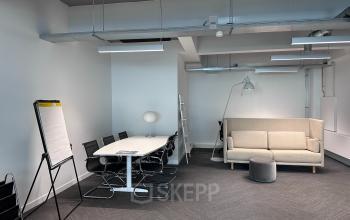 Werkruimte bij kantoor op Beursplein 37, Rotterdam Centrum met vergadertafel, stoelen, whiteboard en bank.