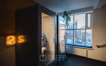 Kantoorpand aan Schiedamse Vest 154, Rotterdam Centrum, met twee privé telefoonhokjes en uitzicht op de stad. Een persoon zit in een van de hokjes.