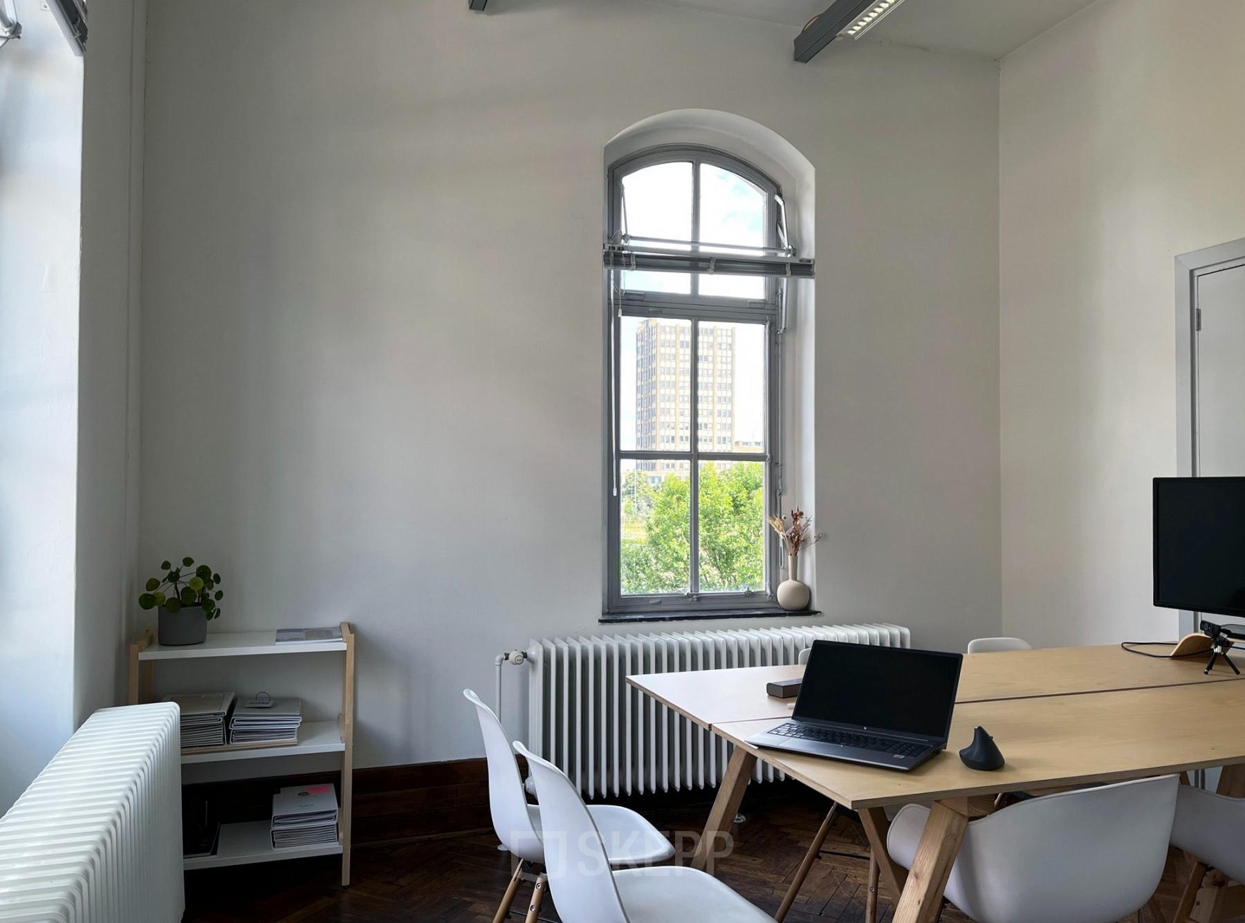 Kantoorruimte huren op Willem Buytewechstraat 45 in Rotterdam Delfshaven met een tafel, stoelen, een laptop en een plank met boeken.