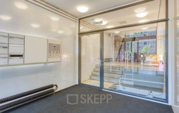 Entree van het kantoorpand op Lloydstraat 21 B, Rotterdam Delfshaven. Moderne glazen deuren geven toegang tot de kantoorruimte huren. Er zijn geen personen aanwezig.
