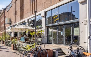 Buitenzijde van een pand aan de Lloydstraat 21 B in Rotterdam Delfshaven met terrassen en enkele fietsen op de voorgrond, ideaal voor kantoorruimte huren.
