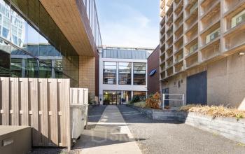 Het exterieur van een modern kantoorpand op Lloydstraat 21 B in Rotterdam Delfshaven, met een open binnenplaats en toegangspad, ideaal voor wie kantoorruimte wil huren.