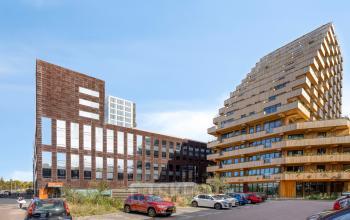 Moderne kantoorpand aan de Kratonkade 7-27 in Rotterdam Delfshaven, omgeven door andere eigentijdse gebouwen en met een ruime parkeerplaats ervoor.