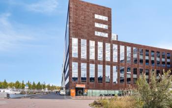 Exterieur van het kantoorpand op Kratonkade 7-27 in Rotterdam Delfshaven, met opvallende spiegelende ramen en moderne uitstraling.