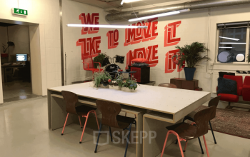 Moderne kantoorruimte huren in Rotterdam Delfshaven, met stijlvolle meubels en inspirerende muurtekening. Ideaal voor creatieve meetings en samenwerking.