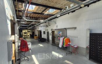 Industrieel kantoorpand op Van Helmontstraat 17-23 in Rotterdam Delfshaven met een moderne inrichting en kleurrijke kledingrekken. Ideale plek voor kantoorruimte huren in een dynamische omgeving.