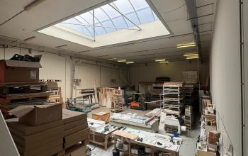 Kantoorruimte te huur in Rotterdam Delfshaven op Van Helmontstraat 17-23, met een grote glazen dakkoepel en diverse werkstations. Ideaal voor creatieve projecten en opslagmogelijkheden.