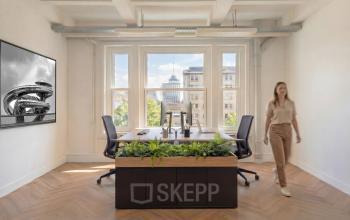 Moderne kantoorruimte op Lloydstraat 5, Rotterdam Delfshaven, met uitzicht op historische gebouwen. De ruimte is voorzien van een groot bureau en comfortabele stoelen, perfect voor bedrijven die kantoorruimte willen huren.