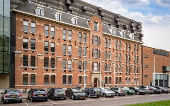 Buitenzijde van een karakteristiek kantoorpand aan de Lloydstraat 5 in Rotterdam Delfshaven met geparkeerde auto's op de voorgrond.