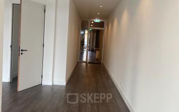 Interieur van kantoorpand Haringvliet 76, Rotterdam, met houten vloer en witte wanden. Gesloten kantoorruimte huren met subtiele verlichting, indruk van een uitnodigende en functionele werkplek.