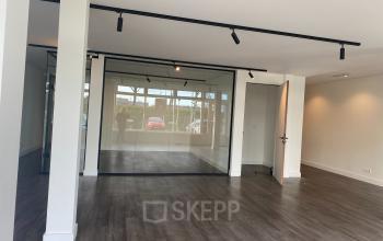 Interieur van een leeg kantoorpand op Haringvliet 76, Rotterdam, met strakke houten vloer en glazen wanden, ideaal voor kantoorruimte huren.