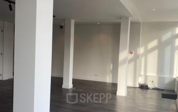 Moderne kantoorruimte huren in Haringvliet 76, Rotterdam met houten vloeren, witte wanden, veel natuurlijk licht en hoog plafond, ideaal voor een creatieve werkomgeving.