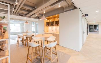 Licht, modern interieur van een kantoorpand op Wilhelminaplein 1-40, Rotterdam Kop van Zuid, met open werkplekken en een sfeervolle koffiehoek. Ideaal voor kantoorruimte huren in een inspirerende omgeving.