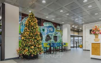 Ingang van een kantoorpand op Oostmaaslaan 71, Rotterdam Kralingen, met kleurrijke muurkunst, hoge stoelen en een feestelijk versierde kerstboom.